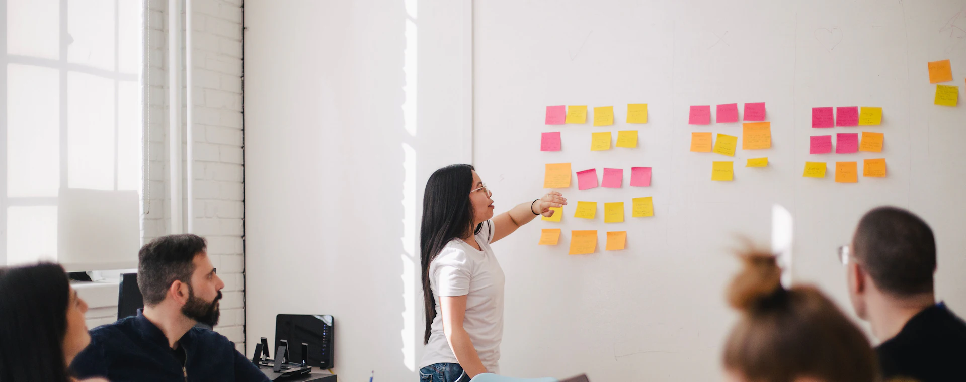 A strategist mapping workflow priorities on sticky notes while the team looks on